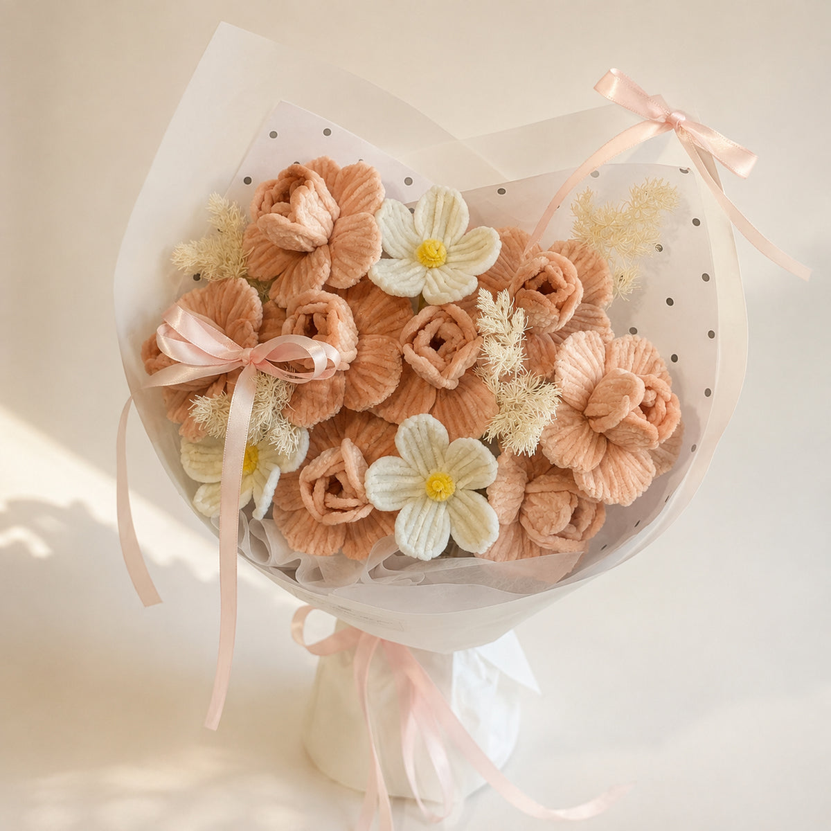 Peach and ivory handmade chenille flower bouquet with white flowers, soft filler, white wrapping and blush ribbons on a warm neutral background.