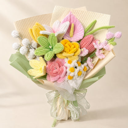 Pastel pink, yellow, green and ivory handmade chenille flower bouquet with cream and pale green wrapping on a warm neutral background.