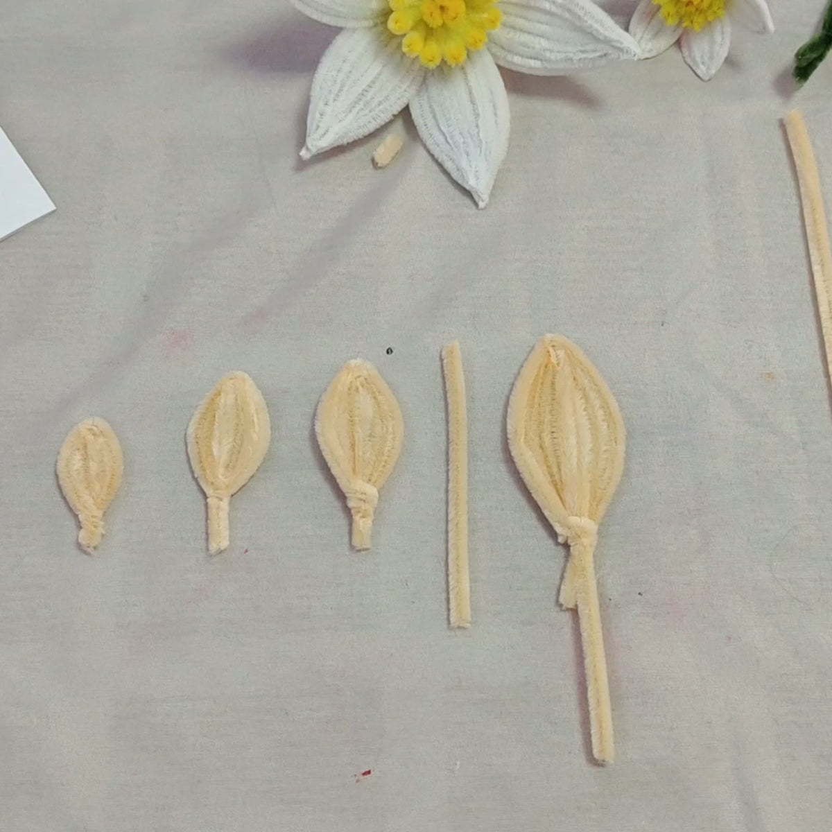 Four sizes of handmade pipe cleaner petals shown in the lesson